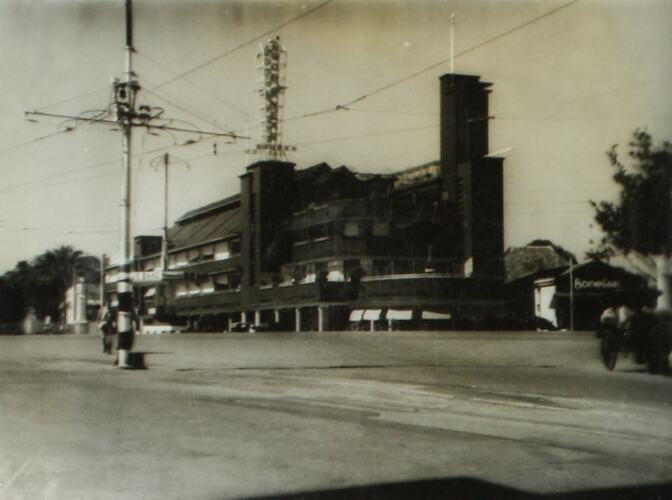 Street scene of a intersection and power lines with building on far corner.