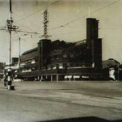 Street scene of a intersection and power lines with building on far corner.