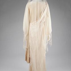 Long-sleaved, cream dress with train and finely-twilled veil.