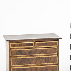 Wooden chest of drawers with light borders.