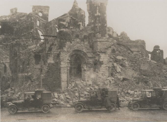 Destroyed cathedral with three motor cars on the road in front of the cathedral.