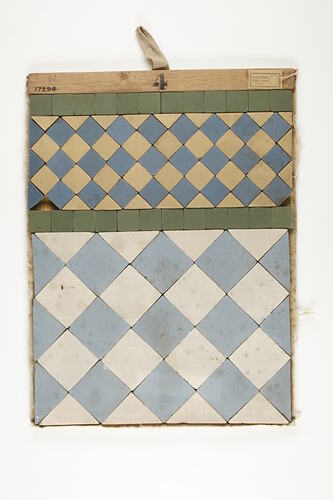 Rectangular mosaic tile. Top has green, yellow,diamond pattern. Base has larger blue, white diamond pattern.