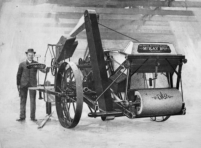 Man standing next to stripper harvester.