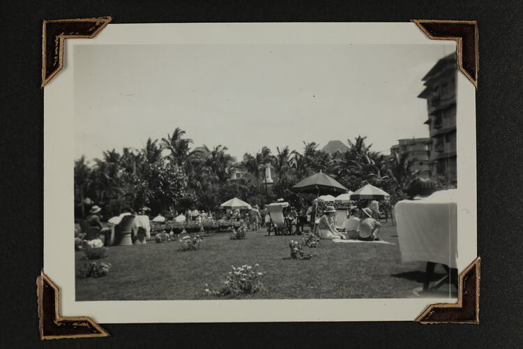 People on a grass lawn, with umbrellas and chairs.