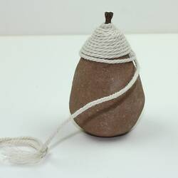 Toy top made from clay and string, side view.