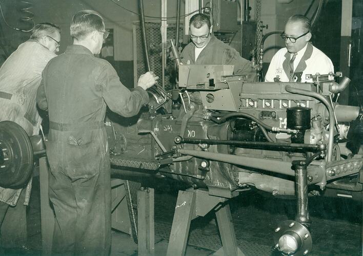 4 men on tractor assembly line.