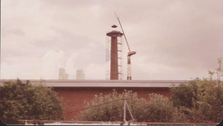 Scaffolding and crane around factory chimney.