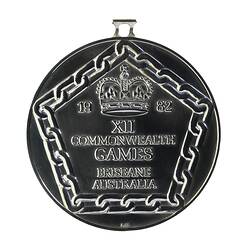 Tarnished silver round medal featuring a pentagonal border framing raised lettering.