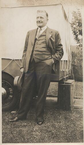 Man in suit standing next to truck.