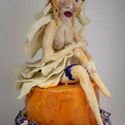 Upper tier of ceramic wedding cake with detail of bride figure.