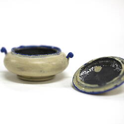 Side view of tiny white pot with lid off.