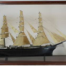 Sailing ship model in glass case, facing right.