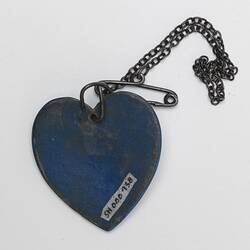 Back of blue heart pendant with metal chain and safety pin.