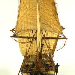 Wooden ship with three masts, front view.