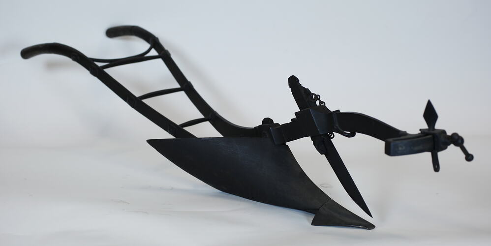 Handheld plough model with large blade, three quarter view.