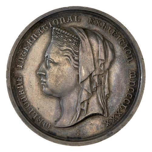 Round silver medal with bust of veiled woman facing left, text around.