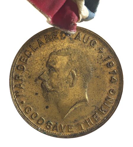 Medal with head of man facing left, text around.