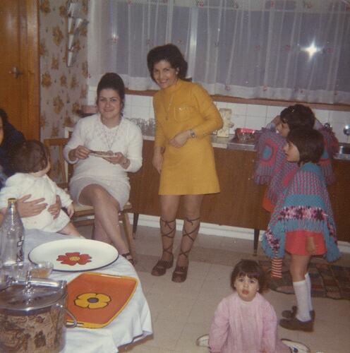 Two smiling women pose in kitchen with four children.