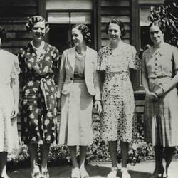 Black and white photo of five women in dresses with short hair.