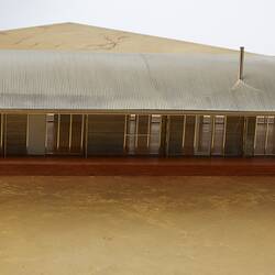 Model of a house with an arched roof, corrugated iron and wide expanses of glass.