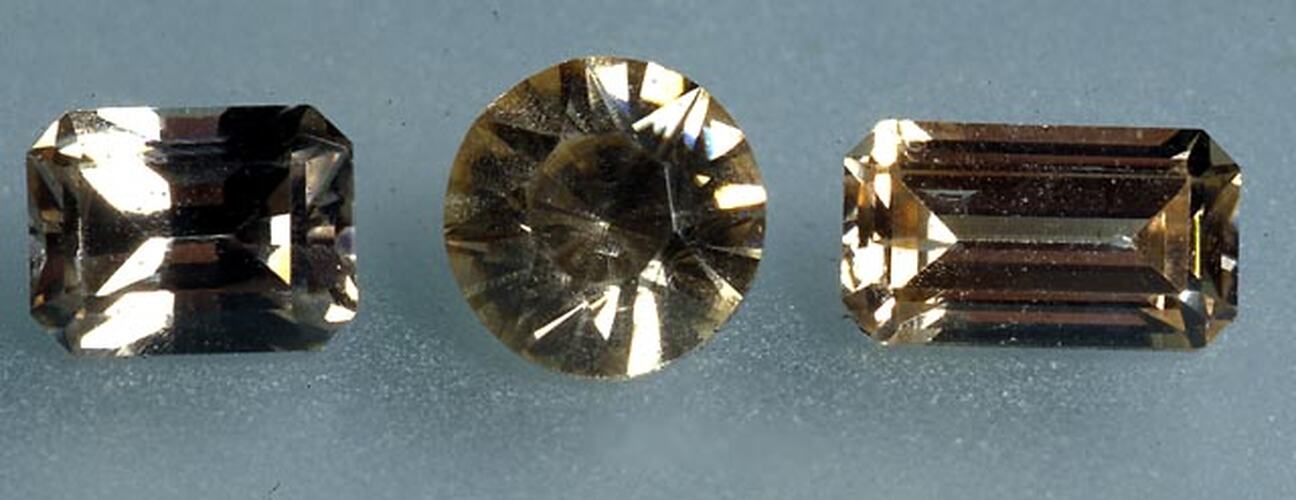Three faceted brown-grey gems.