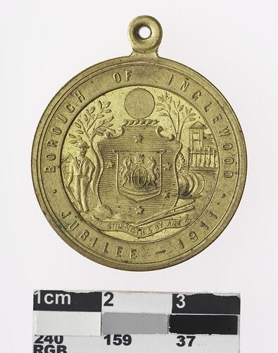 Round gold coloured medal with Australian coat of arms and text surrounding.