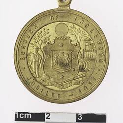 Round gold coloured medal with Australian coat of arms and text surrounding.