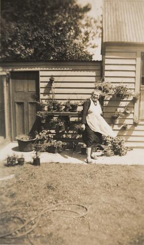 Digital Photograph - Woman Standing in Backyard by Pot Plants, Shed & Aviary, circa 1942