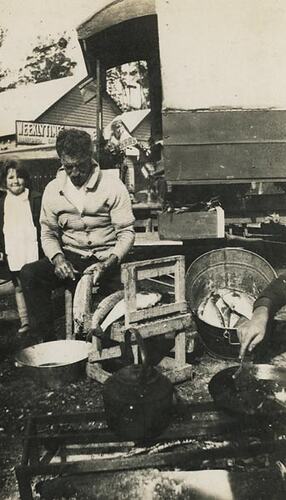 Digital Photograph - Holden Brothers Circus, Man Cleaning Fish with Girl Next to Him, circa 1934