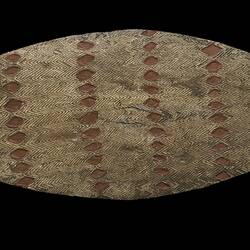 Broad wooden shield with diamond pattern on a black background.