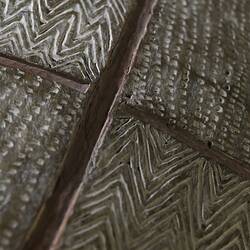 Detail of incised decorations on a wooden shield.