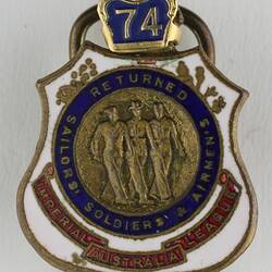 Shield shaped metal badge with white, blue and red enamel and gold trim, with three uniformed men and crown.