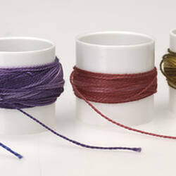 Set of four cotton reels in blue, purple, red and yellowish brown.