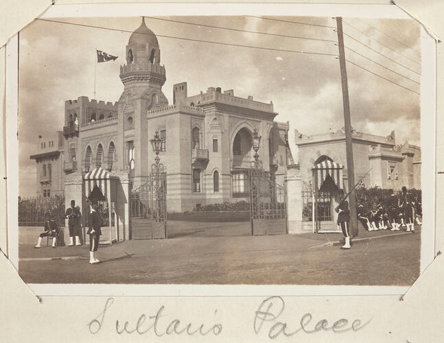 Large stone building with men in military uniform and refills guarding front gate.
