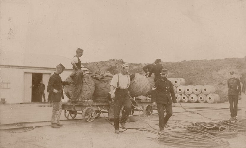 Men with naval mines on rail cart.