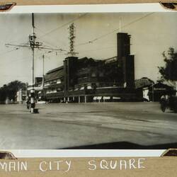 Street scene of a intersection and power lines with building on far corner.