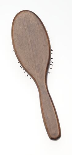 Back of wooden spoon-shaped hairbrush with long handle.
