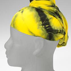 Yellow tie-dyed and topknotted headscarf.