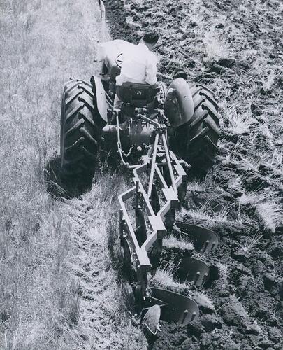 Rear view of mouldboard plough attached to a tractor.