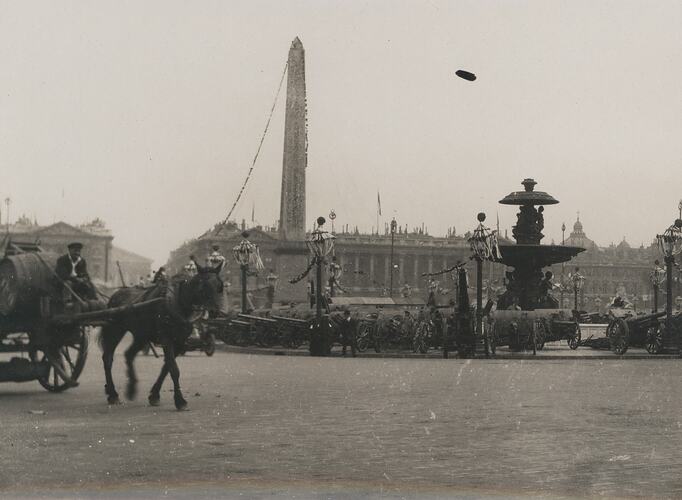 Horse and cart in front of roadway, fountain and obelisk.