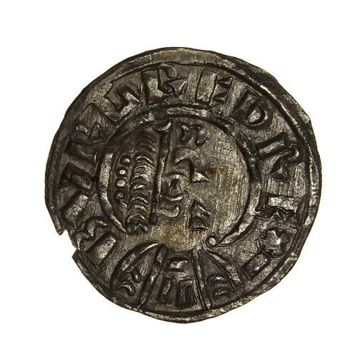 Rough round, dull grey coin with raised characters and pattern. Damaged at lower left.
