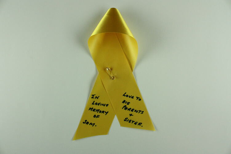 Yellow memorial ribbon with handwritten message.