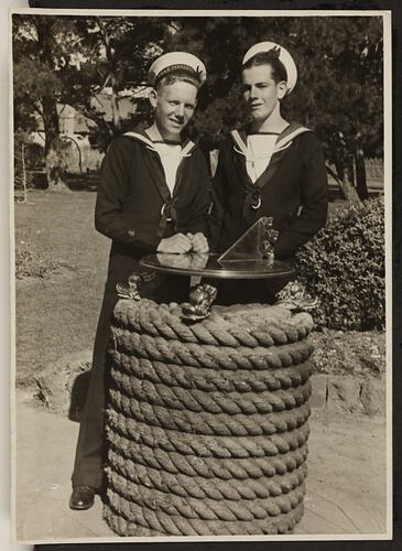 Two Seamen standing behind a sundial with rope wrapped around the base.