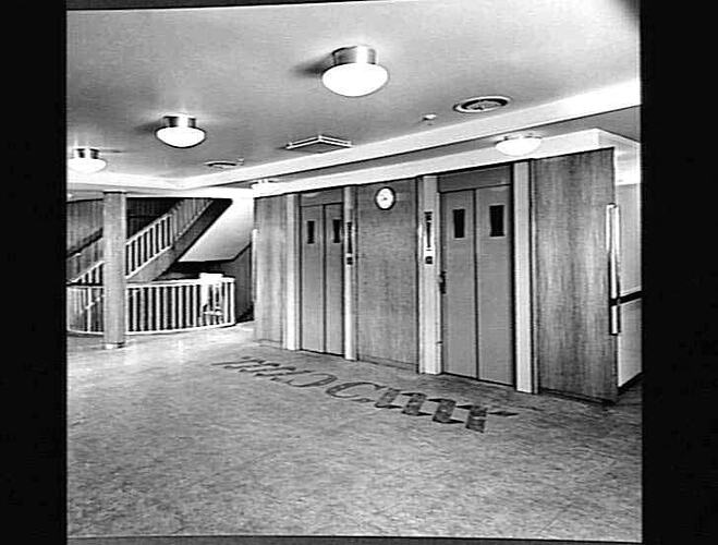 Ship interior. Two sets of sliding doors (lifts?) in central section and a staircase at the left.