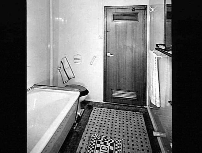 Ship interior. Bath tub and toilet on left, towel rail on right. Door in centre.