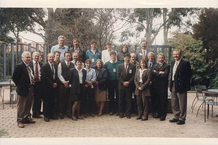 Group of people posing in paved courtyard.