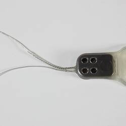 Bionic ear prototype. Round disc with two wires at end.