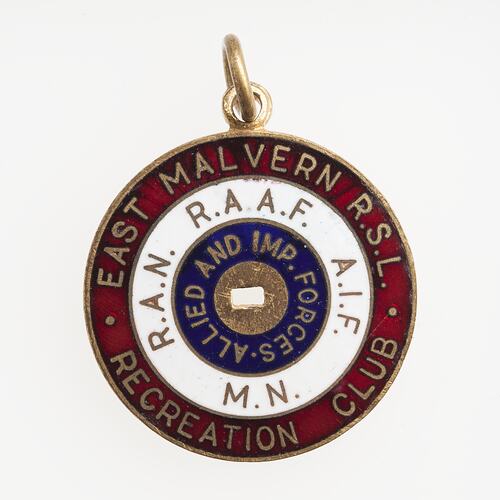 Round metal badge. Red, white, blue enamel circles. Gold text. Rectangular hole in centre. Ring at top.