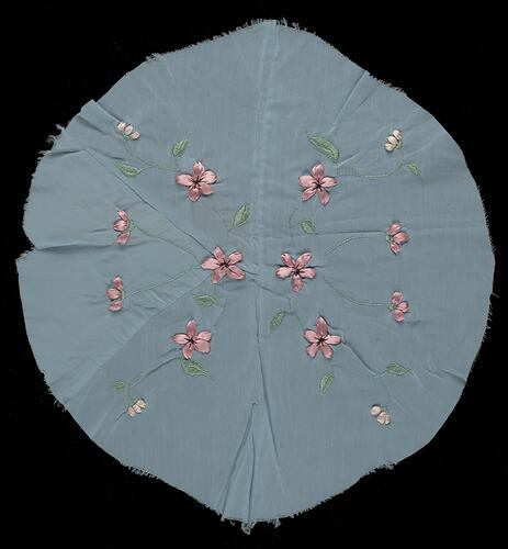 Unfinished circular piece of blue satin material worked with ribbon and cotton embroidery floral pattern.