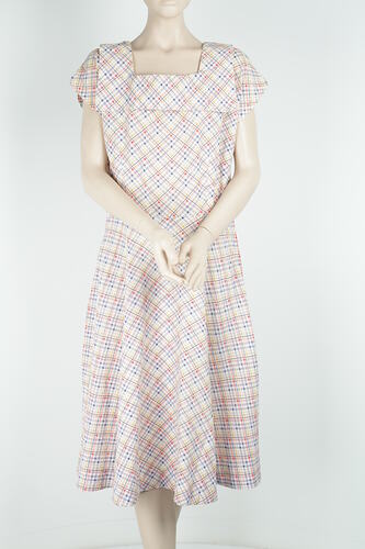 Checked, square-necked sleeveless dress made from white, yellow, blue and red cotton fabric.